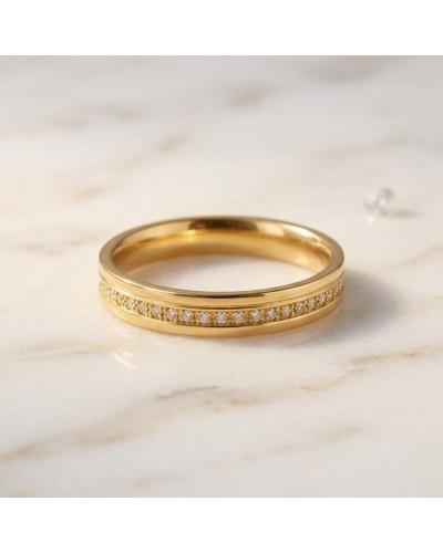 Alliance serti grain de 17 diamants homme en or jaune, près d’une pierre argentée sur fond marbré.