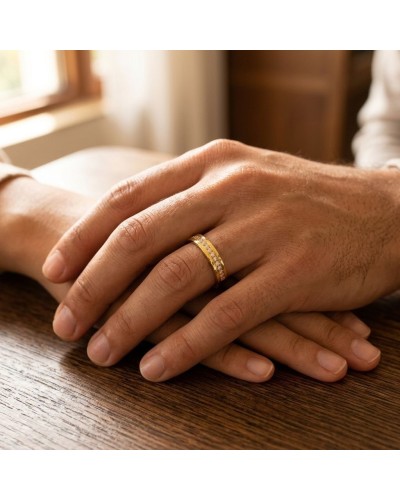 Alliance serti grain de 17 diamants homme en or: doigt masculin portant une bague dorée ornée de diamants sur un fond bois.