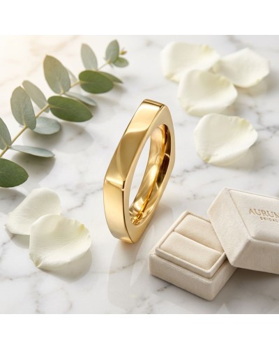 Alliance de forme carrée femme en or, bague dorée lustrée posée sur marbre, avec pétales blancs et branche de eucalyptus en déco