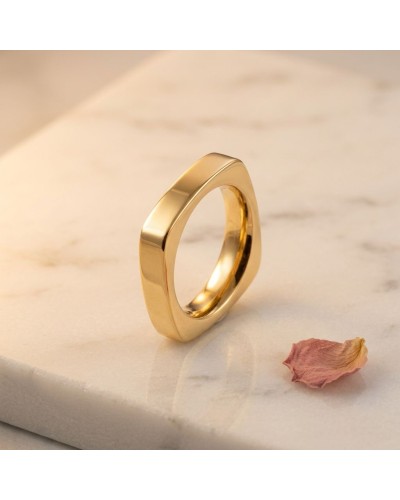 Alliance de forme carrée pour femme en or jaune, bague élégante sur marbre avec pétale rose près.