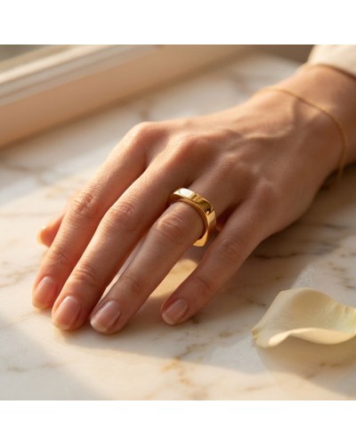 Alliance de forme carrée femme en or: doigt portant une bague dorée carrée élégante sur une main désignée, lumière chaude.