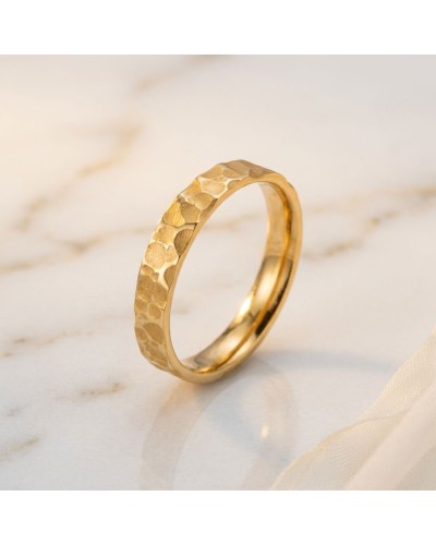 Alliance demi-martelée femme en or jaune, bague fine et texturée posée sur marbre.