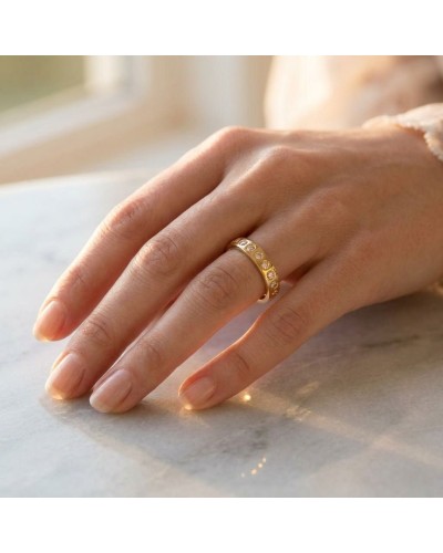 Alliance tour complet 24 diamants femme en or: main feminine portant une bague dorée à pavage de diamants sur une surface claire