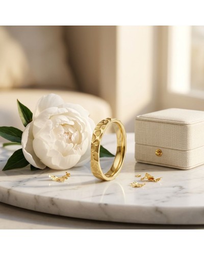 Alliance irrégulière martelée femme en or sur plateau en marbre, avec une pivoine blanche et boîte en satin beige.