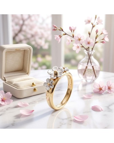 Bague CERISIER en or jaune avec petites fleurs argentées; présentée près d'une boîte à bijoux et d'un vase de fleurs de cerisier