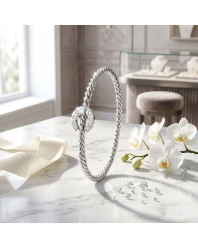 Bracelet ouvrant en argent mat et brillant rhodié avec fermoir circulaire pavé de 6 oxydes blancs, posé sur marbre près d’orchid