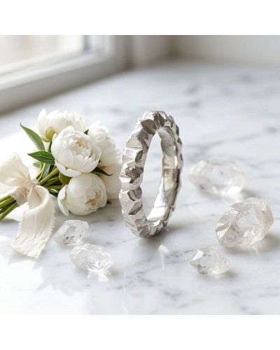 Bracelet argenté texturé posé sur marbre, entouré de fleurs blanches et de petits cristaux translucides. ALLIANCE MARROW FEMME e