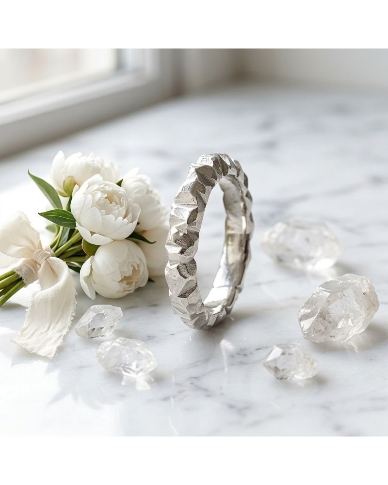 Bracelet argenté texturé posé sur marbre, entouré de fleurs blanches et de petits cristaux translucides. ALLIANCE MARROW FEMME e