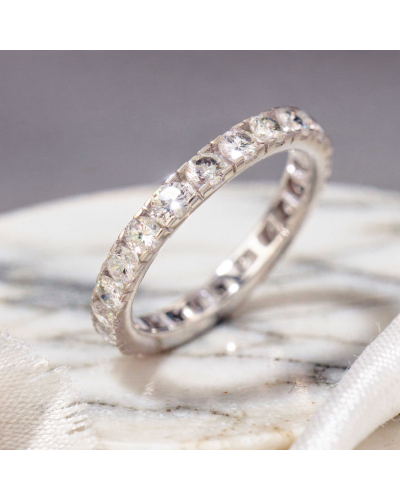 Alliance STAR: bague eternity en platine ou argent avec diamants rondes sertis inset sur tout le tour, posé sur surface marbrée.