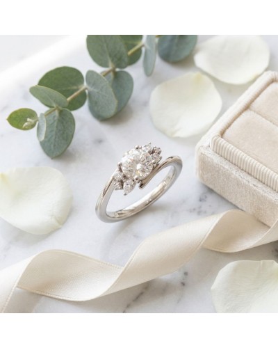 Alliance FLORA femme en or – solitaire or blanc entouré de petits diamants sur bague élégante, coffret beige et pétales.