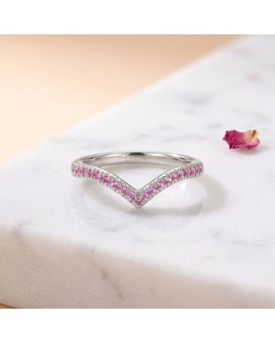 Alliance TIANA femme en or: délicate bague argentée en forme de V ornée de petits rubis roses sur le rebord, posée sur marbre av