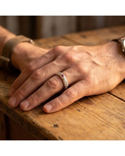 Alliance BISON homme en or: doigt portant bague texturée avec pierre rouge sur une table en bois.