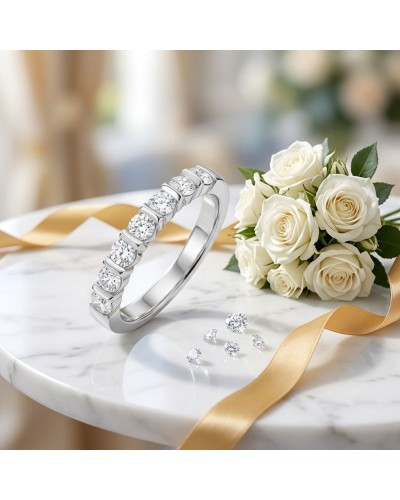 Alliance NAUSICAA femme en or avec diamants sur un bracelet émeraude argenté, bouquet de roses blanches et ruban doré sur marbre