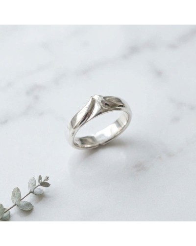 Alliance BUFFLE homme en or : bague argentée à motif incurvé sur fond marbré avec brin de végétal au premier plan