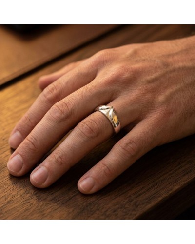 Alliance BUFFLE homme en or: bague masculine en or sur le doigt, près d’une table en bois.