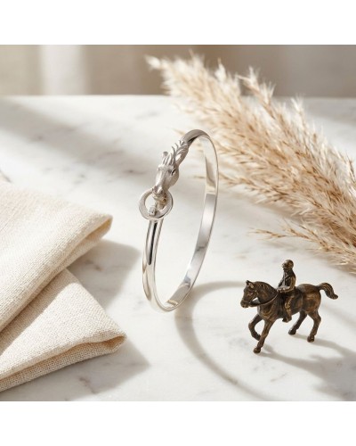 Bracelet argent mat et brillant rhodié posé sur marbre, motif dragon autour du fermoir, décor rustic avec épis et cheval miniatu