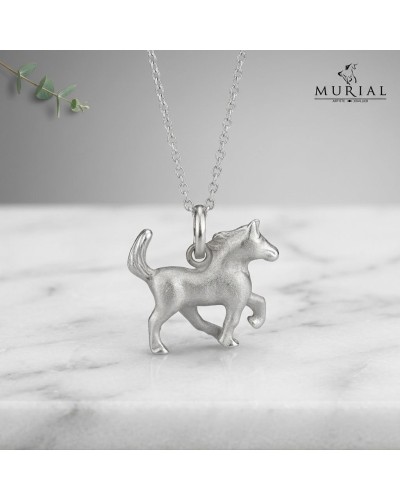 Pendentif argenté en forme de cheval, accroché à une chaîne, sur fond gris clair. Parfait pour le collier "Un pendentif HOPE" de