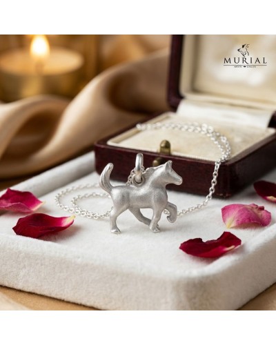 Pendentif en forme de chien argenté HOPE sur chaîne argentée, posé près d’une boîte à bijoux ouverte avec pétales rouges.