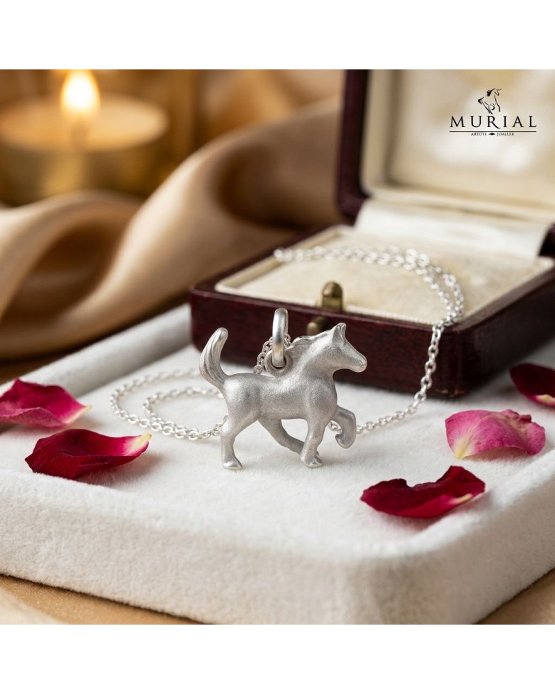 Pendentif en forme de chien argenté HOPE sur chaîne argentée, posé près d’une boîte à bijoux ouverte avec pétales rouges.