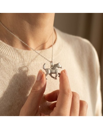 Pendentif cheval argenté en forme de chevalier HOPE sur chaîne, porté près du cou d’une personne, tenue beige.