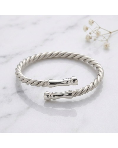 Bracelet torsadé argenté avec extrémités bouchonnées, style bangle ouvert et poli, posé sur marbre. ALT: bracelet GALOPADE argen