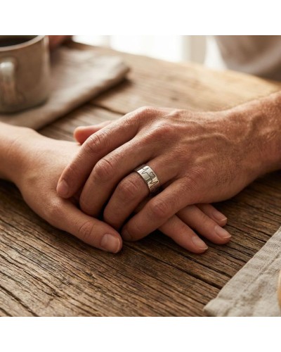 Alliance BEATING LOVE homme en or: duo de mains jointes sur table en bois, homme porte bague argentée gravée.