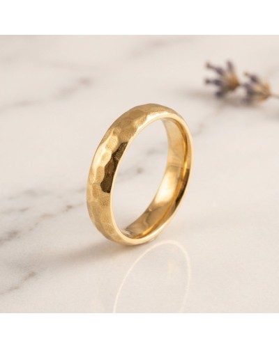 Alliance homme en or bombée avec un effet martelé, prise en gros plan sur anneau doré texturé.