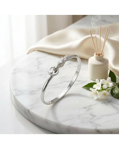 Bracelet ARABE en argent mat et brillant rhodié avec dragon, posé sur une table en marbre, décor floral et diffuseur.