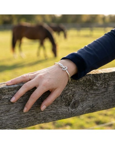 Bracelet mixte en argent rhodié brillant et mat porté au poignet d’une main posée sur une barrière en bois, arrière-plan champ e