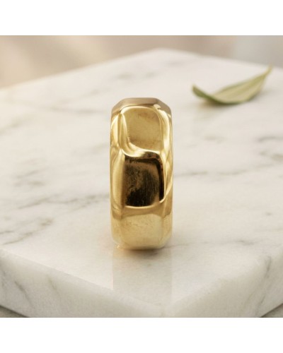 Alliance en écrou lisse pour homme en or jaune, bague masculine épurée posée sur une surface blanche.
