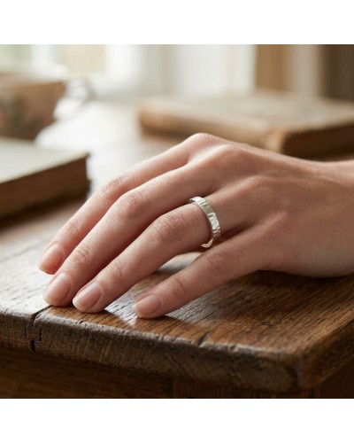 Alliance BASALTE 4 mm Femme en or: bague argentée facettée portée sur doigt près d’une table en bois.