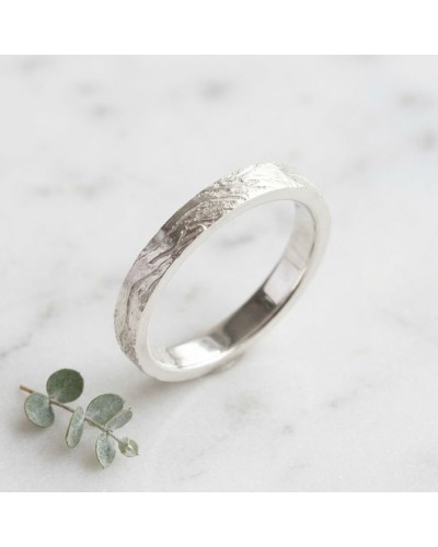 Alliance CIME 4 mm Femme en or: bague argenté avec texture martelée et lame intérieure lisse, posé sur marbre avec brin de eucal