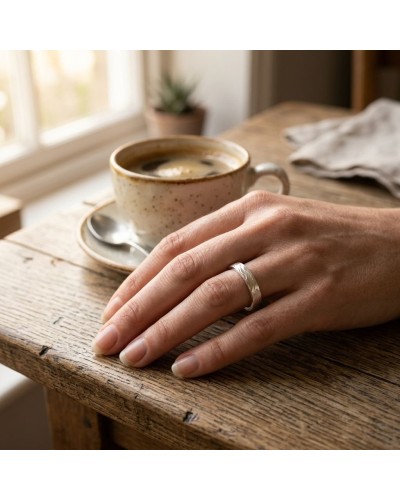 Alliance CIME 4 mm Femme en or sur le dos d’une main posée sur une table en bois, près d’un café.