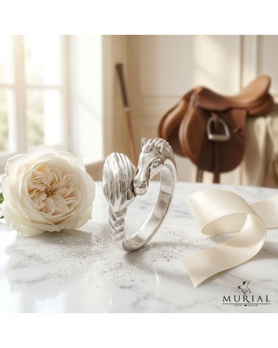 Bague argentée MIKA en forme de dragonne enroulée sur un doigt, avec voile satin et rose blanche en arrière-plan.