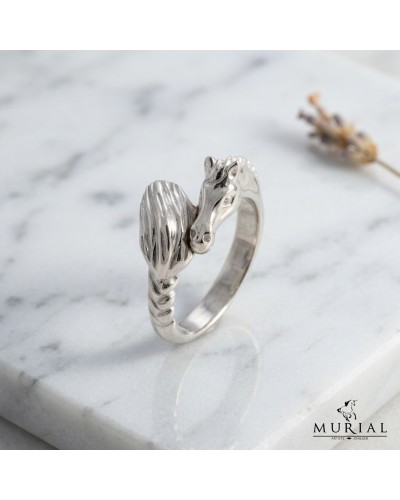 Bague MIKA en argent, motif tordu avec une tête de dragon ou animal stylisé autour d’un anneau sculpté, posé sur une surface bla