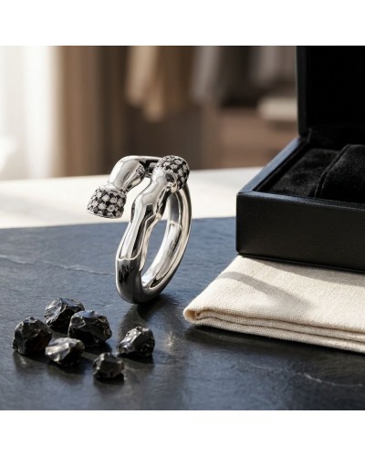 Bague PIAFFER homme en argent rhodié avec 42 oxydes noirs brillants, design sculptural près d’un coffret noir et pierres noires.
