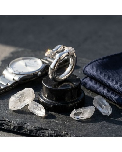 Bague PIAFFER homme en argent rhodié avec 42 oxydes blancs, posée sur socle noir, autour quartz clair et montre argentée.
