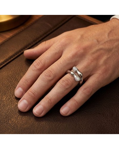 Bague PIAFFER homme en argent rhodié avec 42 oxydes blancs, portée sur le doigt, près d’un meuble en cuir.