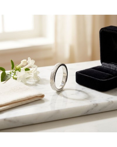 Alliance CIME 4 mm Homme en or: bague argentée posée sur marbre, près d’un écrin noir et de fleurs blanches.