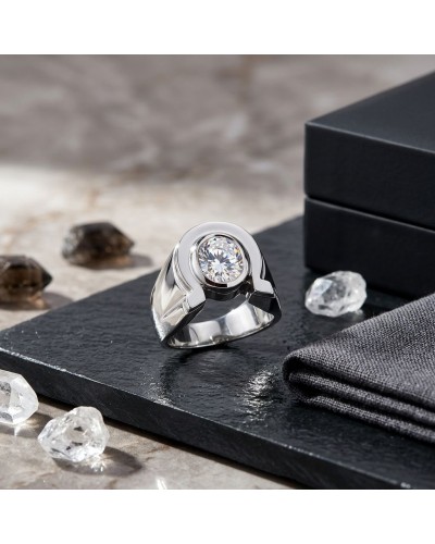 Chevalière homme en argent rhodié with a central round white opal-like stone, displayed on black slate with crystal decor.