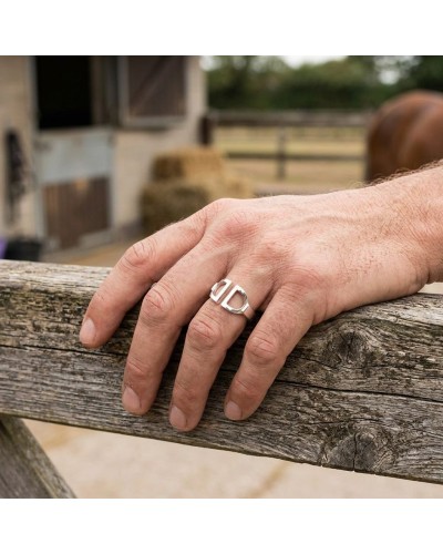 Bague homme en argent rhodié posée sur une main posée sur une barrière en bois, près d’un décor rural.