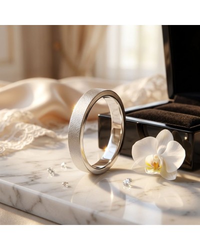 Alliance SABLE 4 mm Homme en or: une bague argentée brillante posée sur un marbre, entourée d'une orchidée blanche et de bijoux