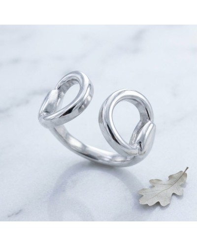 Bague MORS homme en argent rhodié : anneau ouvert double hélice argenté posé sur marbre avec feuille en bas à droite.