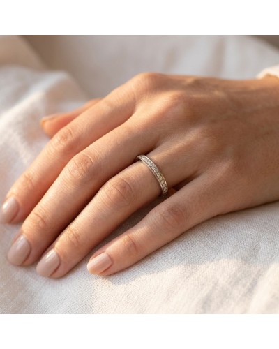 Alliance féminine fine en or avec pierres scintillantes de 3 mm, portée sur le doigt d’une main.