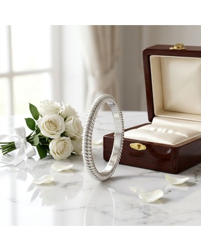 Alliance ELEKTRA 3 mm femme en or: bracelet argenté torsadé posé près d'une boîte à bijoux en bois et des roses blanches.