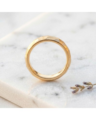Alliance FLASH 4 mm homme en or: bague masculine dorée avec facettes, vue de profil sur pierre blanche.
