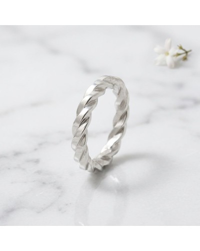 Alliance torsadée en or 4 mm pour femme, bague élégante sur fond blanc avec fleur en déclairage.