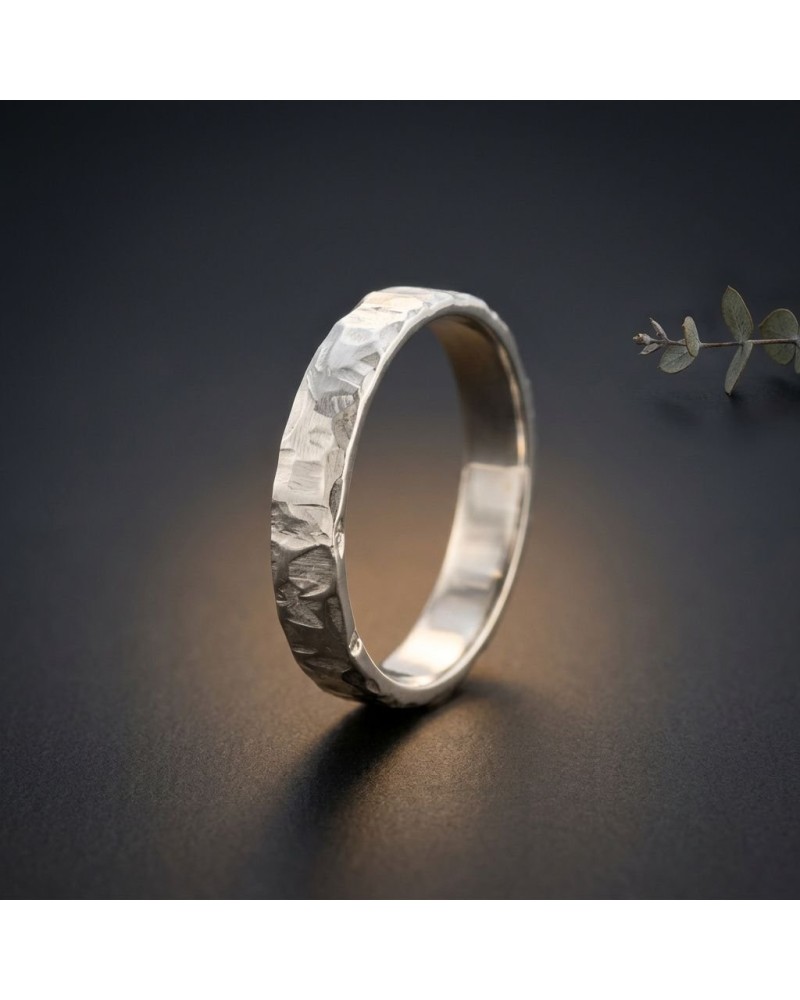 Alliance FRAGMENT 4 mm Homme en or: bague argentée à texture sculptée sur fond sombre, légère lumière chauffante.