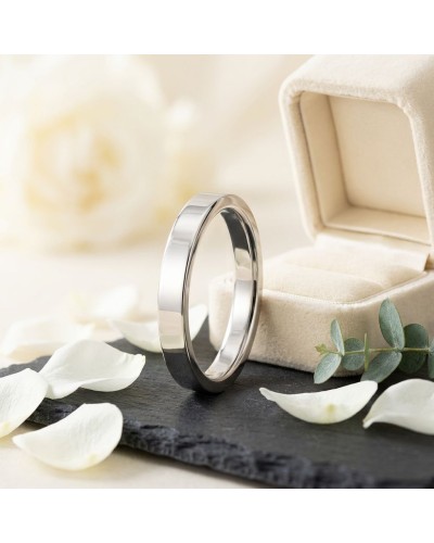 Alliance MATRIX lisse 4 mm homme en or: bague masculine argentée en métal poli près d'un boîtier beige, pétales blancs autour.