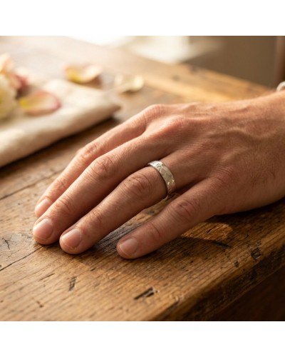Alliance FUSION 4 mm Homme en or: doigt d'un homme portant une bague d'apparence argentée sur une table en bois.